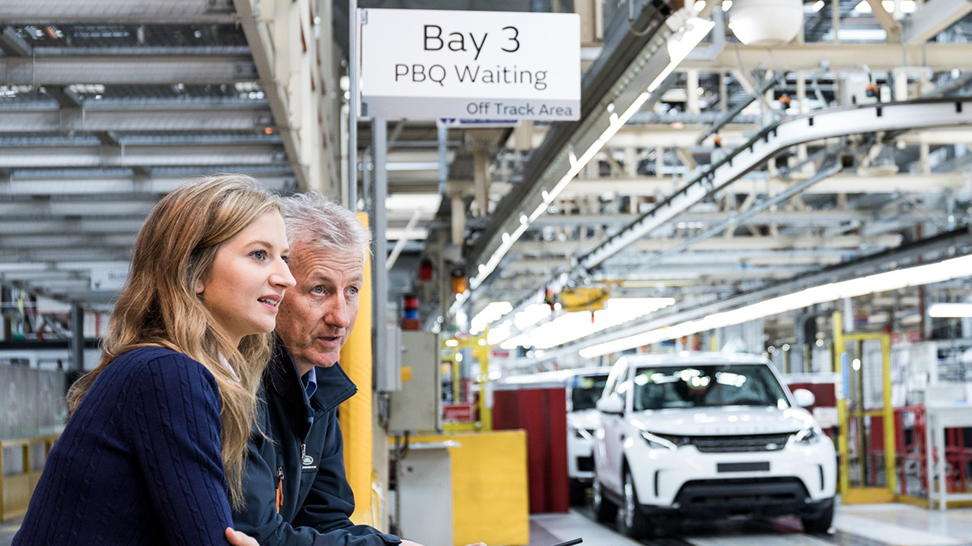 Two people viewing how Jaguar Land Rover vehicles are produced.