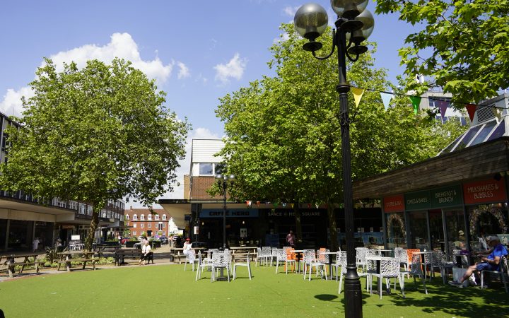 A sunny day in Mell Square, looking towards Mill Lane and Warwick Road through the lush green trees.